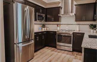 Modern kitchen with stainless gas range, overhead hood, microwave, and refrigerator.