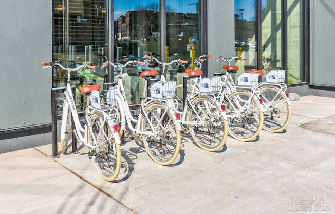 A row of bicycles are parked in front of a building.
