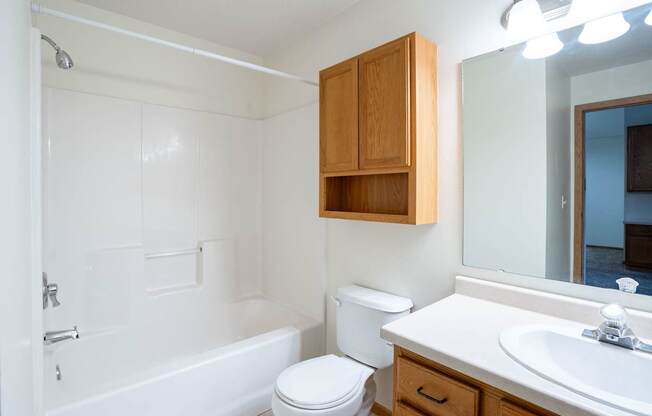 A white bathroom with a toilet, sink, and bathtub. Fargo, ND Summit Point Apartments
