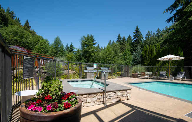 a resort style pool and hot tub in a backyard with trees