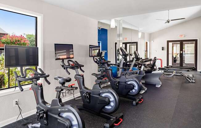 Modern fitness room with stationary bikes, cardio equipment, and bright natural light.