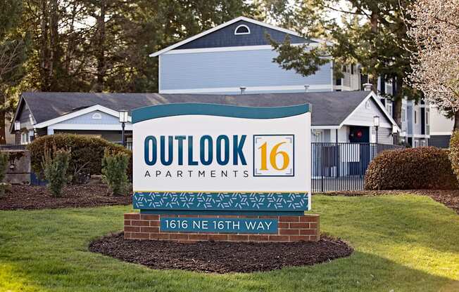 a sign that says outlook 16 apartments with a house in the background