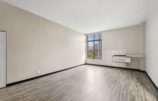 an empty living room with white walls and wood floors and a window