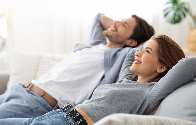 a man and a woman laying on a couch in the living room