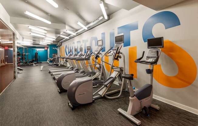 A gym with a row of exercise bikes and a wall with the word
