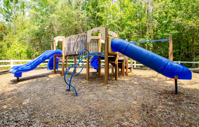 a playground with a blue slide and a wooden bench