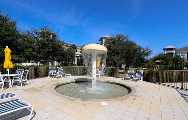 A fountain in the middle of a patio surrounded by chairs.