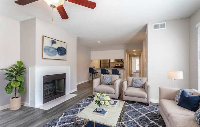 A living room with a fireplace, a ceiling fan, and a painting on the wall.