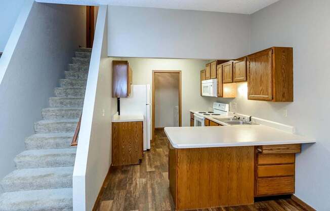 a kitchen with a sink and a refrigerator next to stairs at Creekstone Falls, Sioux Falls, SD, 57106
