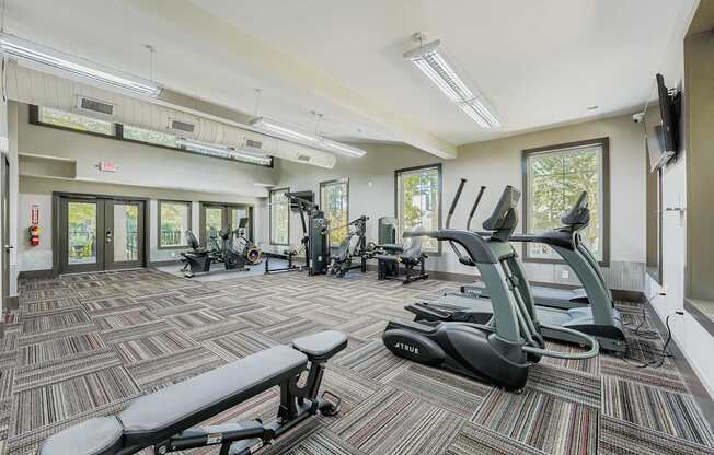 A gym with a variety of equipment including treadmills, exercise bikes, and weights.