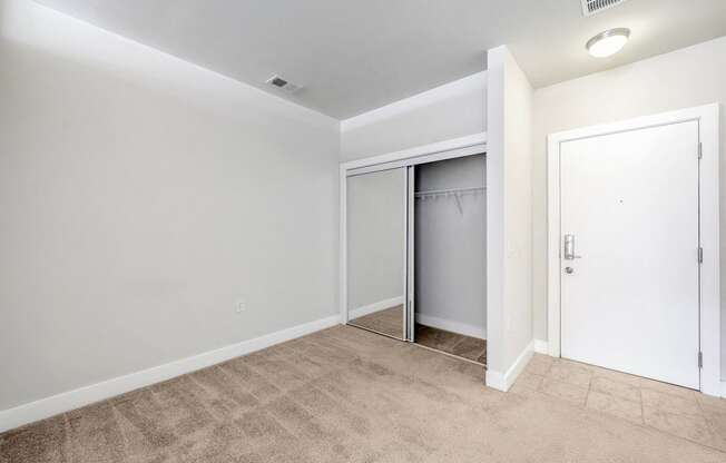 A room with a white door and a carpeted floor.