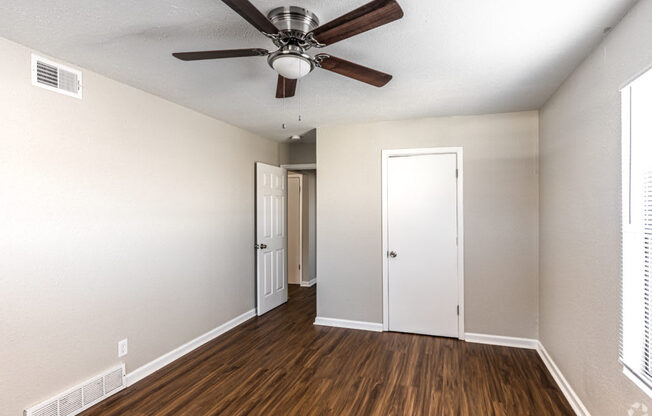 A room with a ceiling fan and wood flooring.
