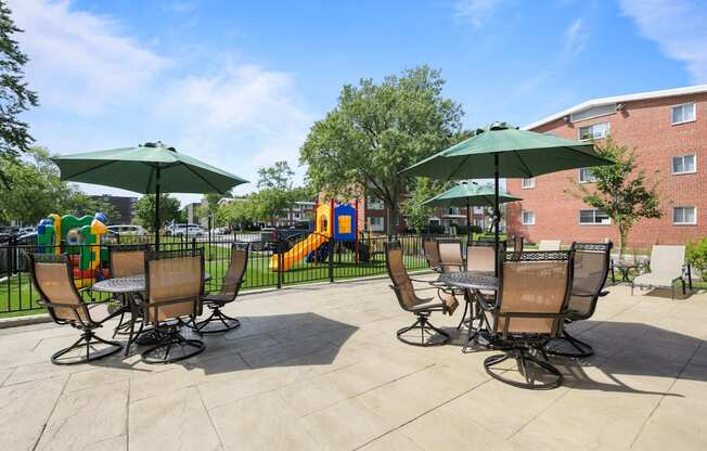 an outdoor patio with chairs and umbrellas and a playground