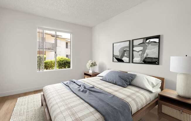 A bedroom with a bed, nightstand, and a window with a view of a building outside.