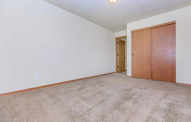 A room with a carpeted floor and a wooden door.