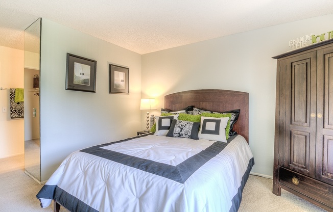 A bedroom with a large bed and a wooden cabinet.