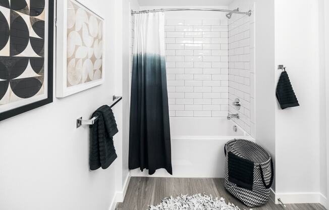 a white bathroom with a black shower curtain and a white tub