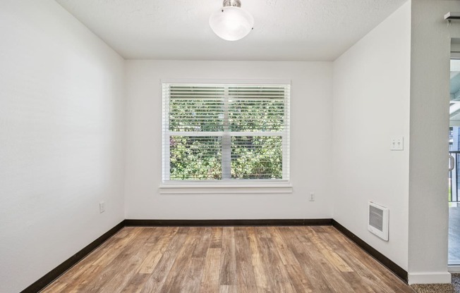 A room with a window and wooden floors.