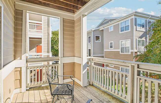 A balcony with a table and chairs overlooks a residential area.