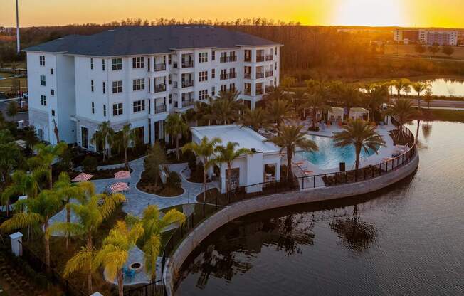 A resort with a pool and palm trees at sunset.
