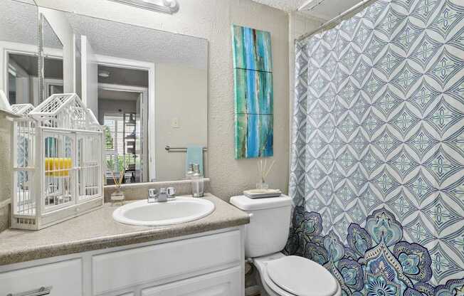 A bathroom with a white toilet, sink, and a birdcage on the counter.