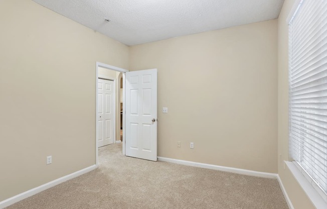 A room with a white door and carpeted floor.