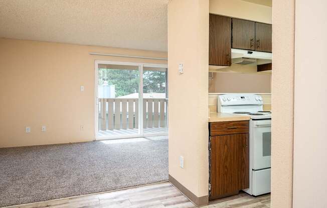 A kitchen area with a white fridge and a window with a view of a fence.