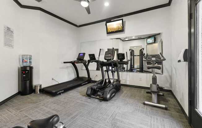 A gym with a variety of equipment including treadmills, elliptical machines, and weights.