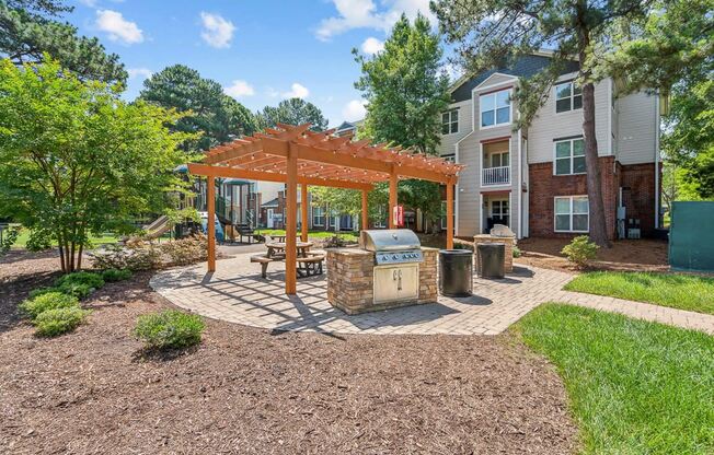 a patio with a picnic table and a grill