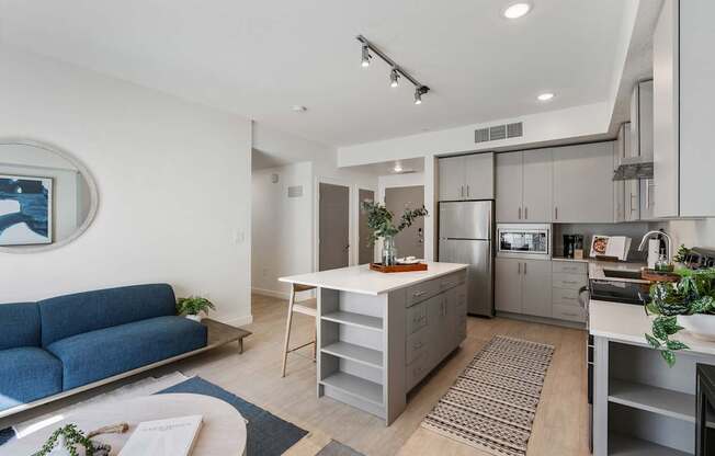 a living area with a kitchen and a blue couch