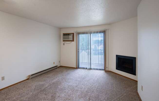 an empty living room with a fireplace and a sliding glass door. Fargo, ND Westview Towers Apartments