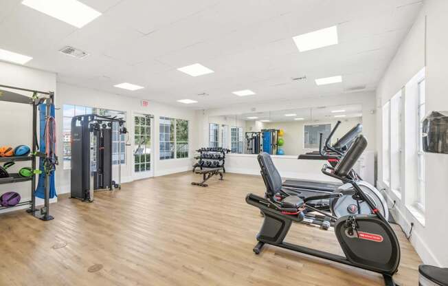 A gym with a row of treadmilers and a squat rack.