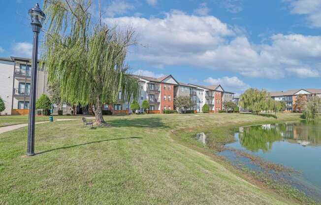 A serene pond with benches and apartment buildings in the background at Ultris Island Park in Shreveport, LA