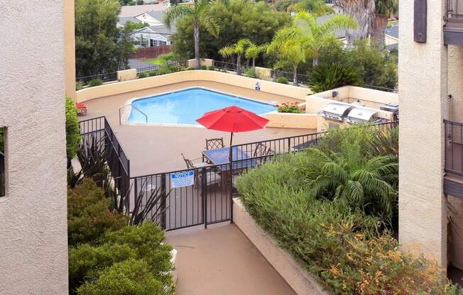 a view of a pool from a balcony with a red umbrella