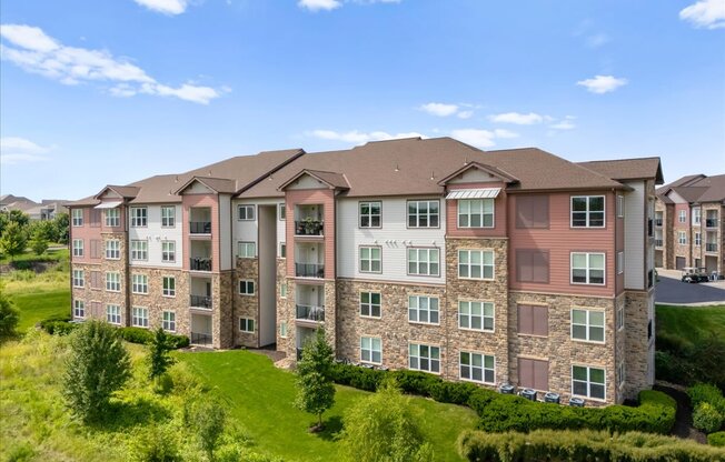A large apartment building with multiple balconies and a green lawn in front.
