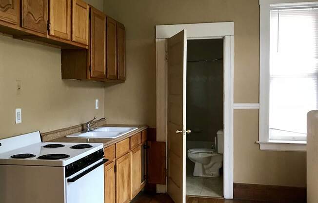 an empty kitchen with a stove and a door to the bathroom