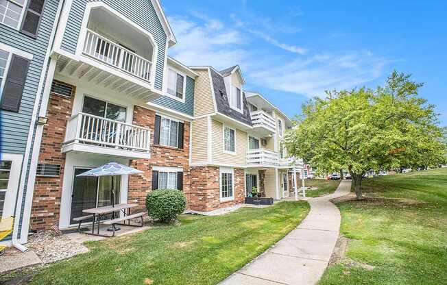 A sunny day at a building with a patio and balconies and a clear blue sky at Apple Ridge Apartments, Michigan, 49534