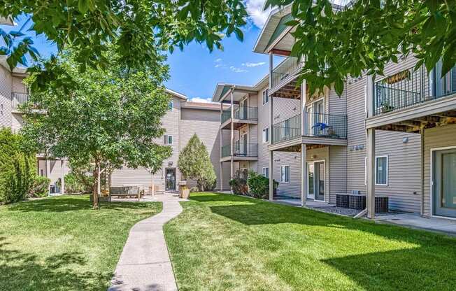 a walkway between two apartment buildings with grass and trees