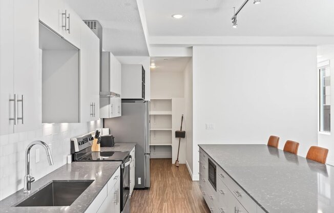 A modern kitchen with a sink, stove, and refrigerator.