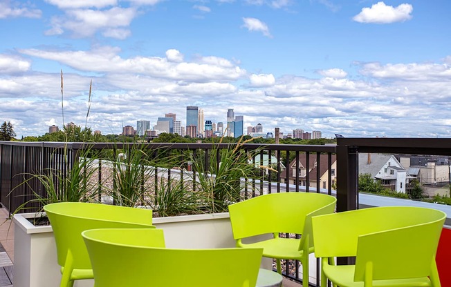 A balcony with four chairs and a table overlooking a city skyline.