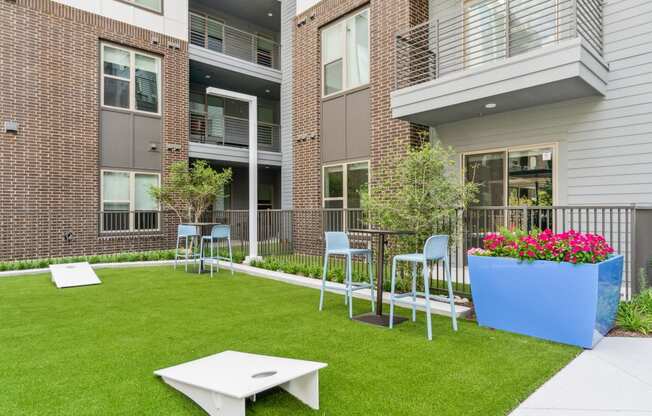 a yard with a table and chairs in front of an apartment building