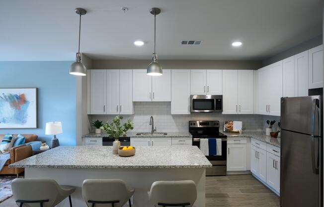 a kitchen with white cabinets and a marble counter top