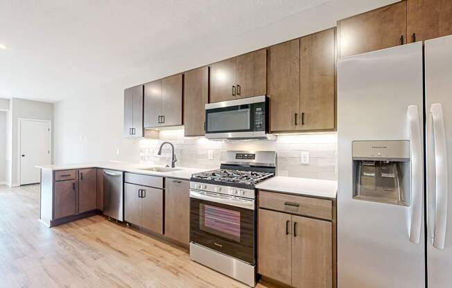 A modern kitchen with a stainless steel refrigerator, microwave, and oven.