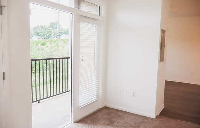 an empty living room with a door to a balcony