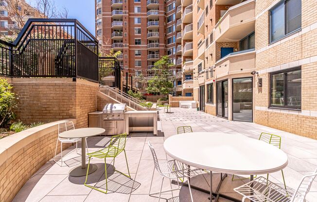 a patio with tables and chairs and a grill