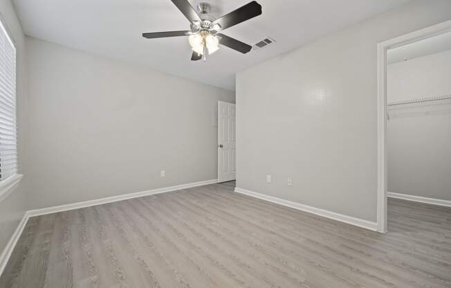 an empty bedroom with a ceiling fan