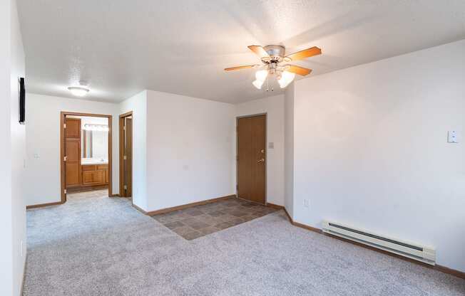 the living room and dining room of an empty house with a ceiling fan. Fargo, ND Oxford Apartments