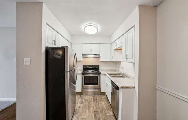 A kitchen with a black refrigerator and white cabinets. at Glen at Lakewood, Colorado