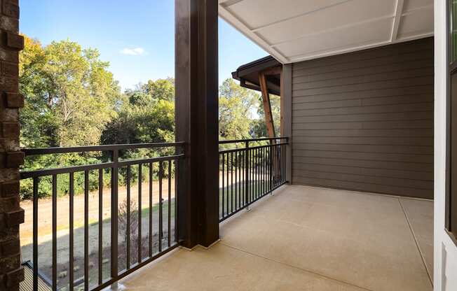 A balcony with a black railing and a view of trees.