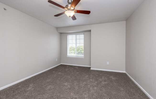 an empty room with a ceiling fan and a window